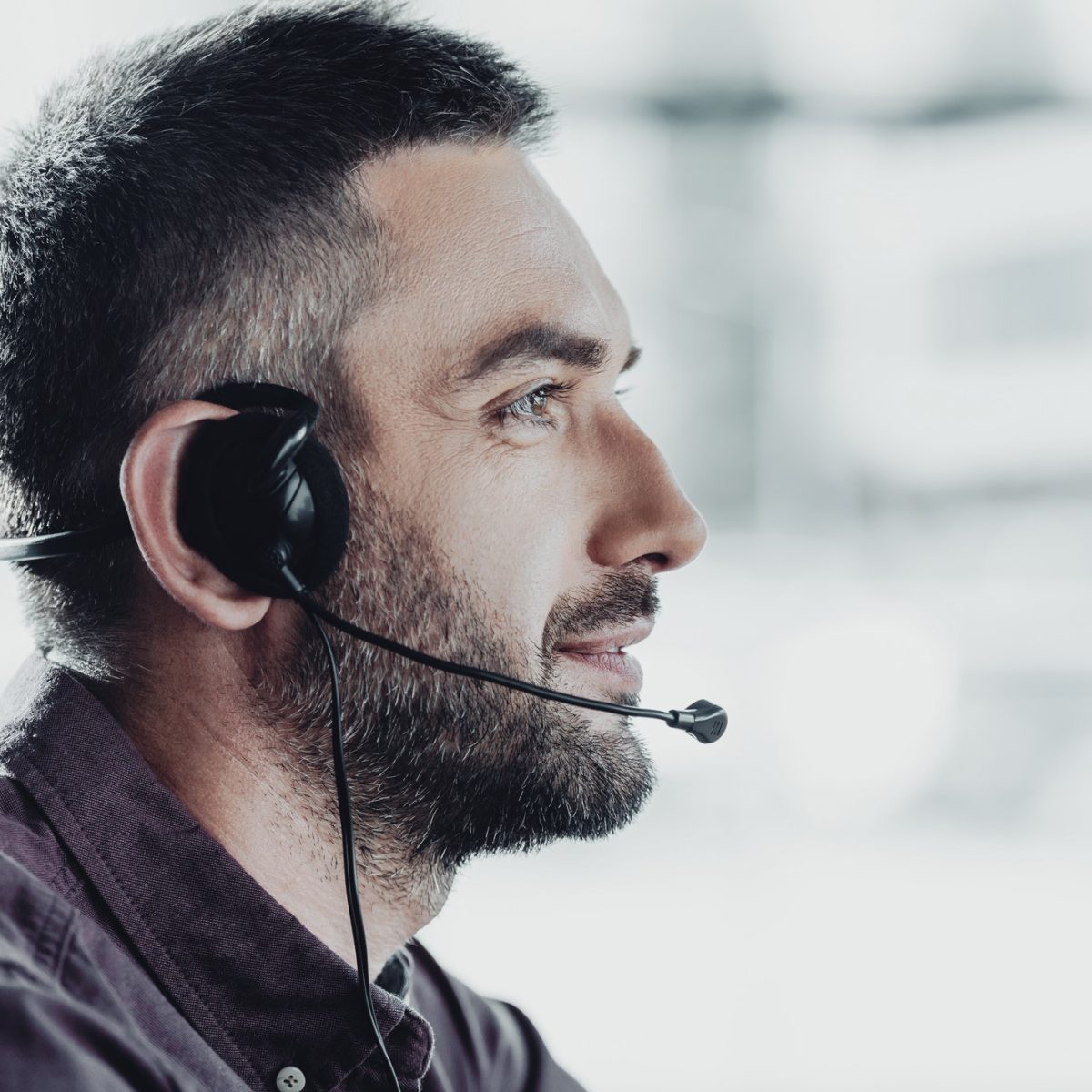 side view of handsome call center worker in headphones with microphone